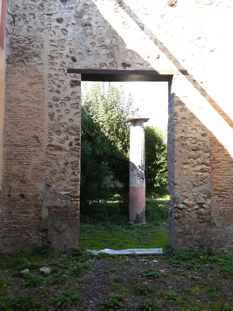 The ruins of Pompeii with Mount Vesuvius rising behind — the forum colonnade, basalt street paving, and the volcano that buried the city in 79 AD. UNESCO World Heritage since 1997.